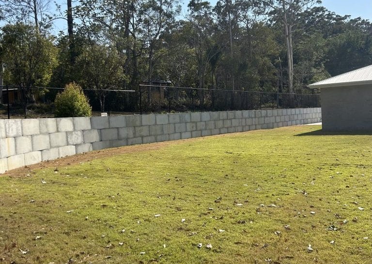 Completed residential retaining wall with proper drainage design supporting a landscaped yard
