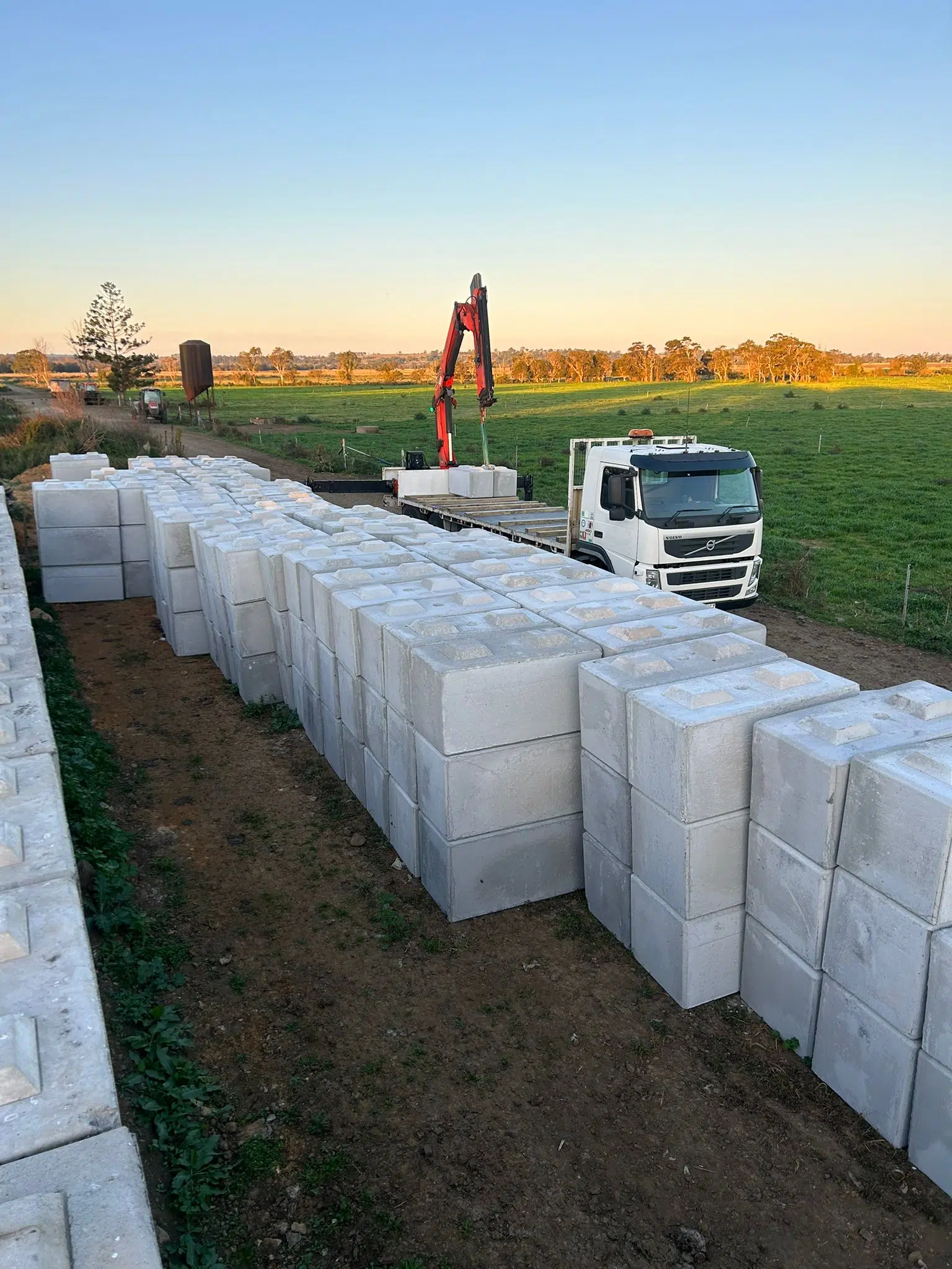 Stacks of large sustainable concrete blocks being delivered by a truck in a rural area, representing sustainable building materials for eco-friendly construction.