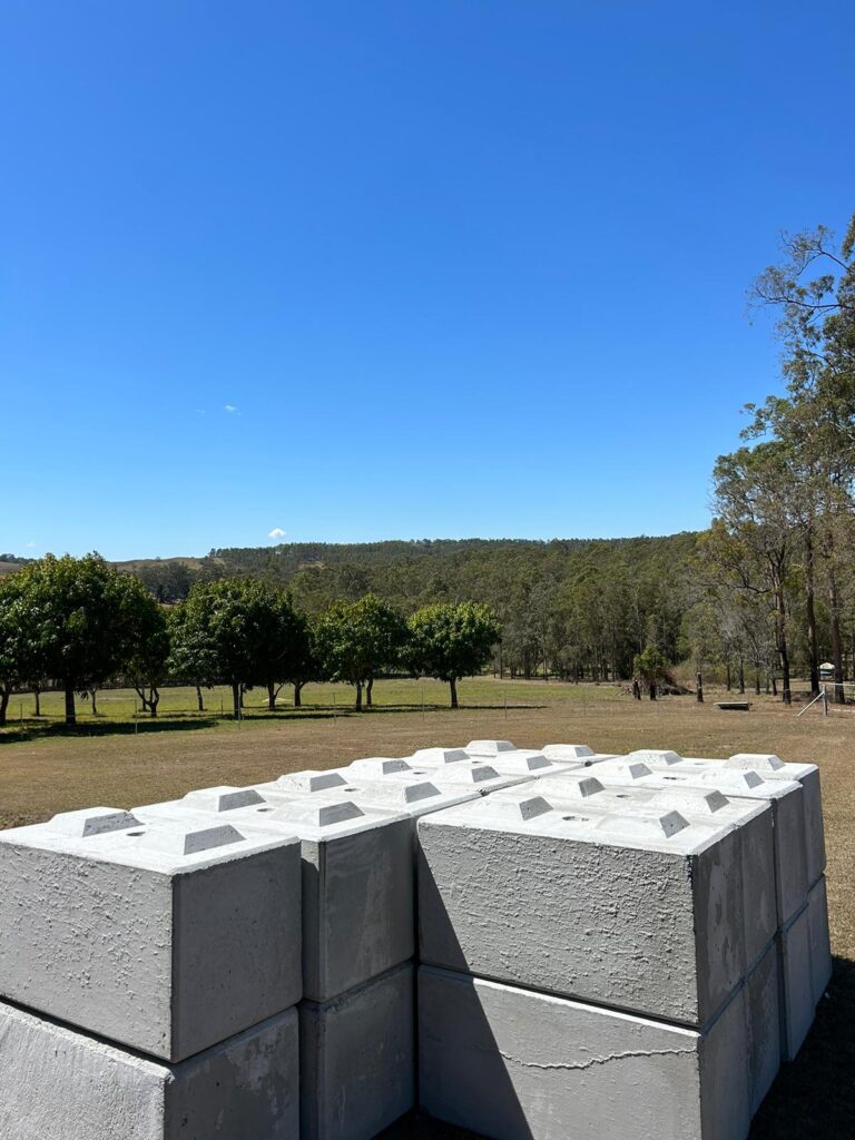 Stacked precast concrete blocks in Australia placed in a rural outdoor setting with green trees and clear sky