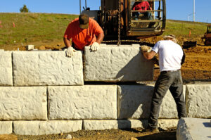 Construction workers building a retaining wall with drainage systems in a coastal area to prevent erosion and flooding.