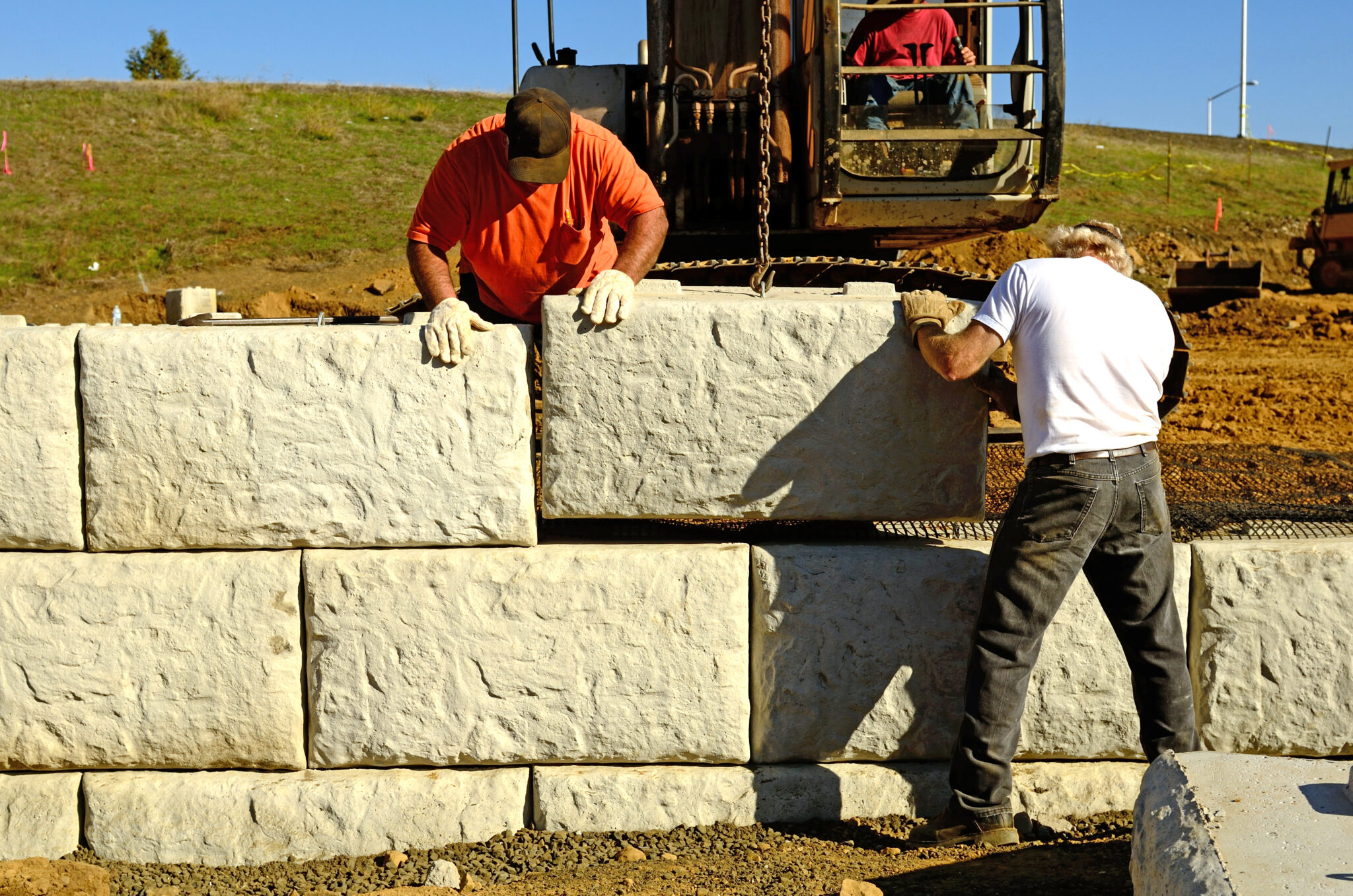 Construction workers building a retaining wall with drainage systems in a coastal area to prevent erosion and flooding.