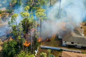 A wildfire approaching residential homes, highlighting the importance of fire-resistant precast concrete construction for property protection