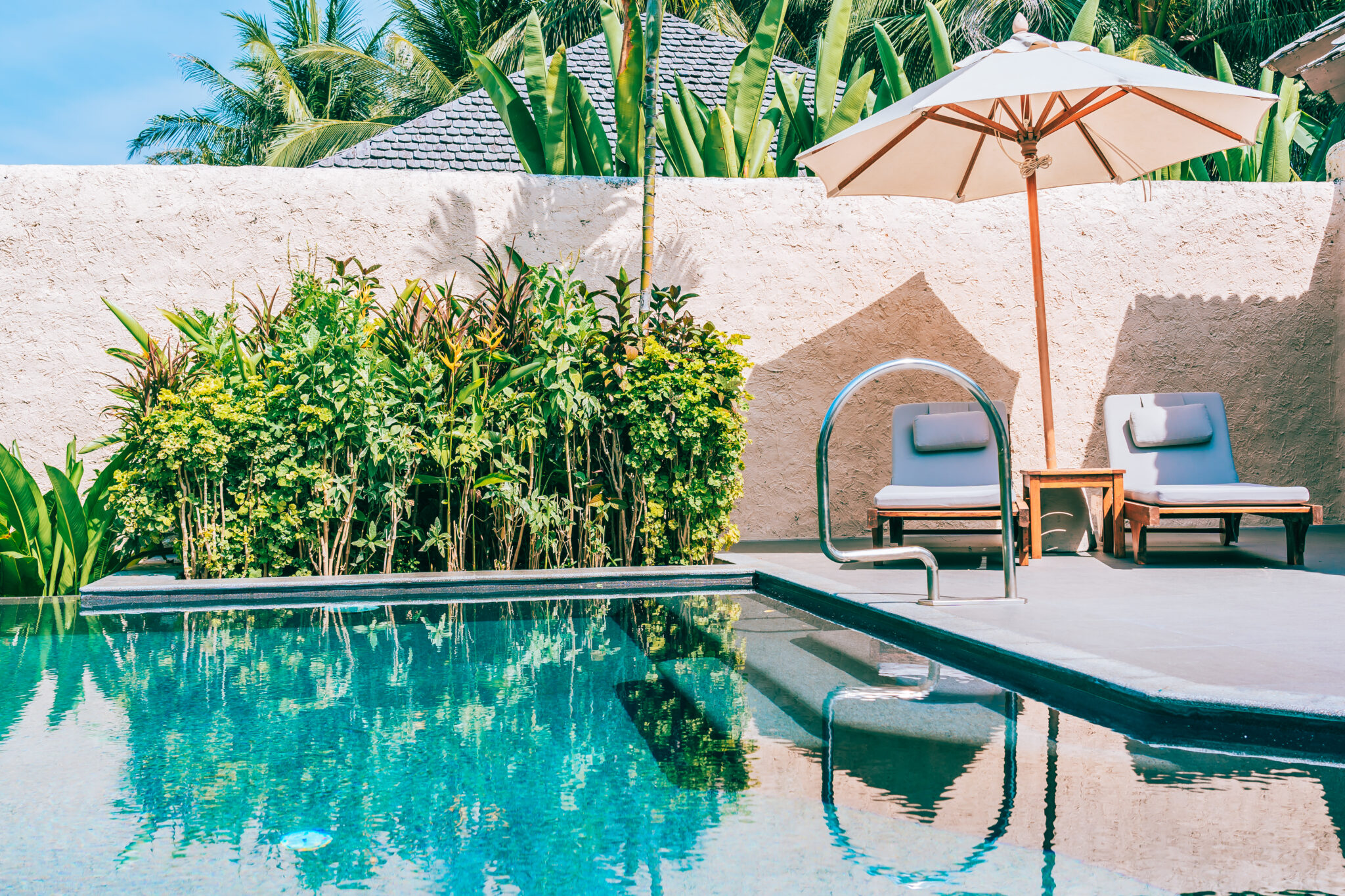 Resort-style pool area with lounge chairs and umbrella used in Gold Coast pool landscaping design.