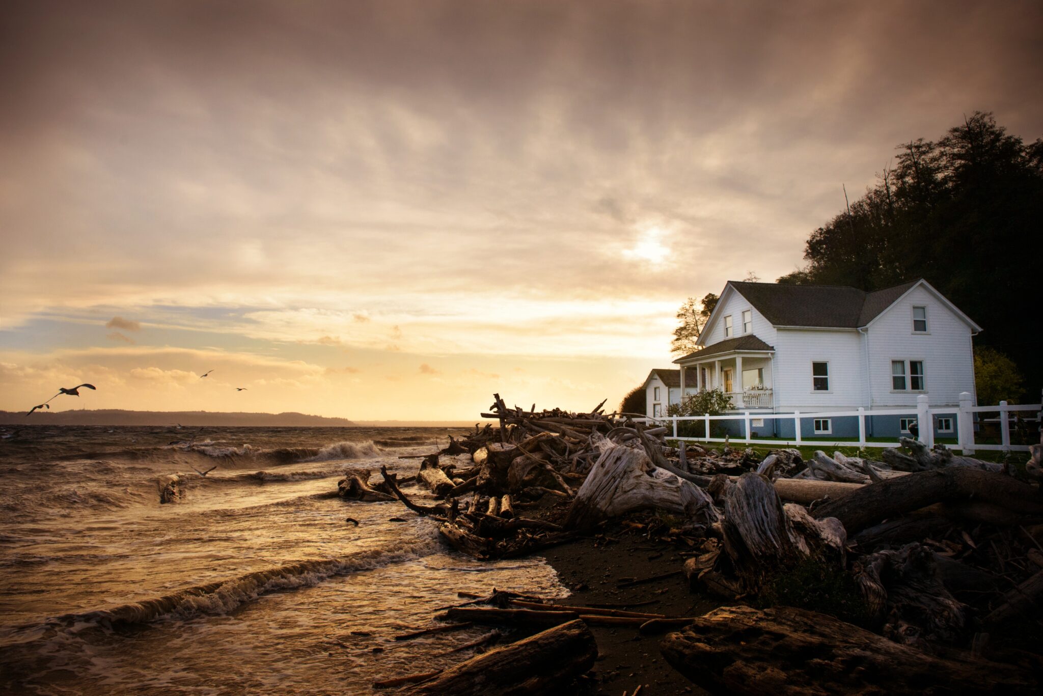 A coastal house near the shoreline at sunset, highlighting the importance of storm-resistant materials like precast concrete for coastal homes.