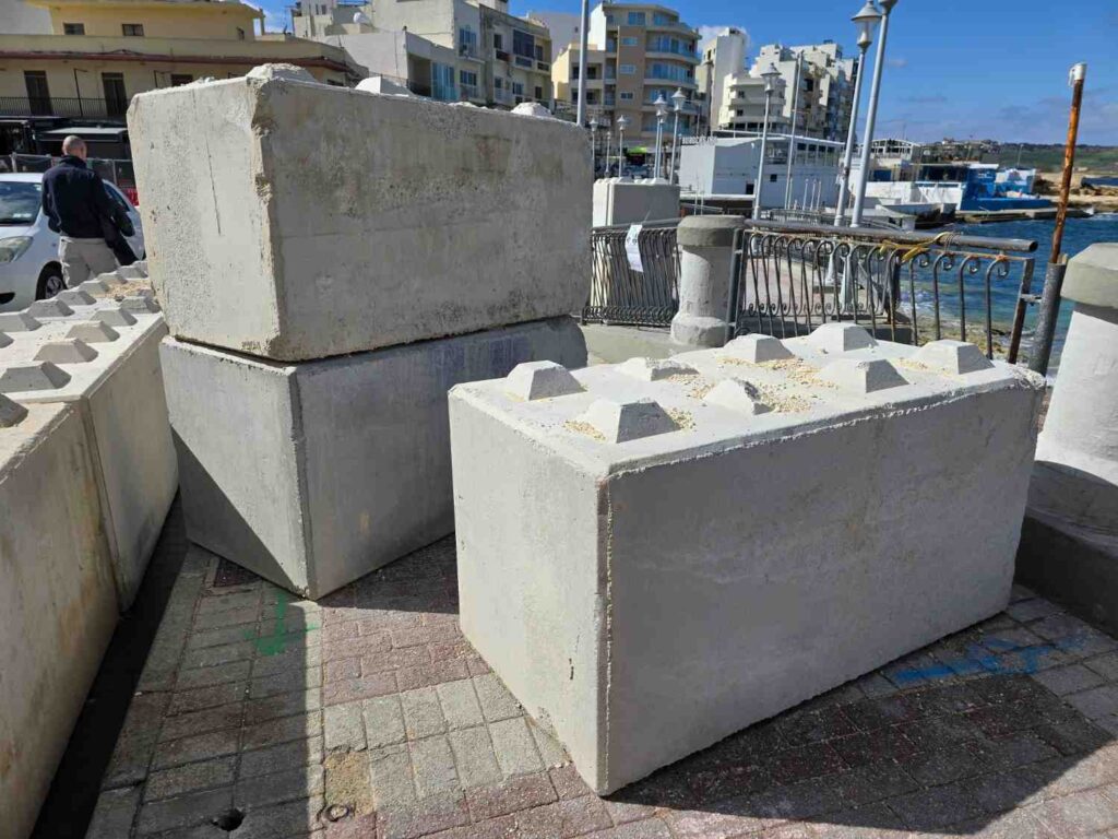 Precast concrete for coastal homes used as heavy barrier blocks along a seaside promenade to protect waterfront properties from waves and erosion.