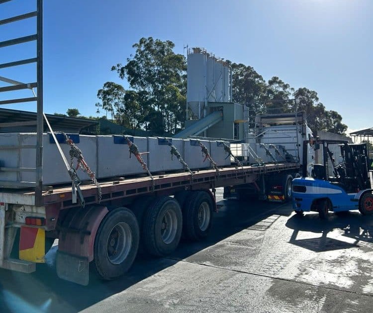 Precast concrete supplier in SEQ delivering large precast concrete blocks on a flatbed truck at an industrial site.