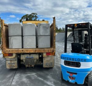 Precast concrete supplier in SEQ loading recycled concrete blocks onto a truck using a forklift at a concrete yard.