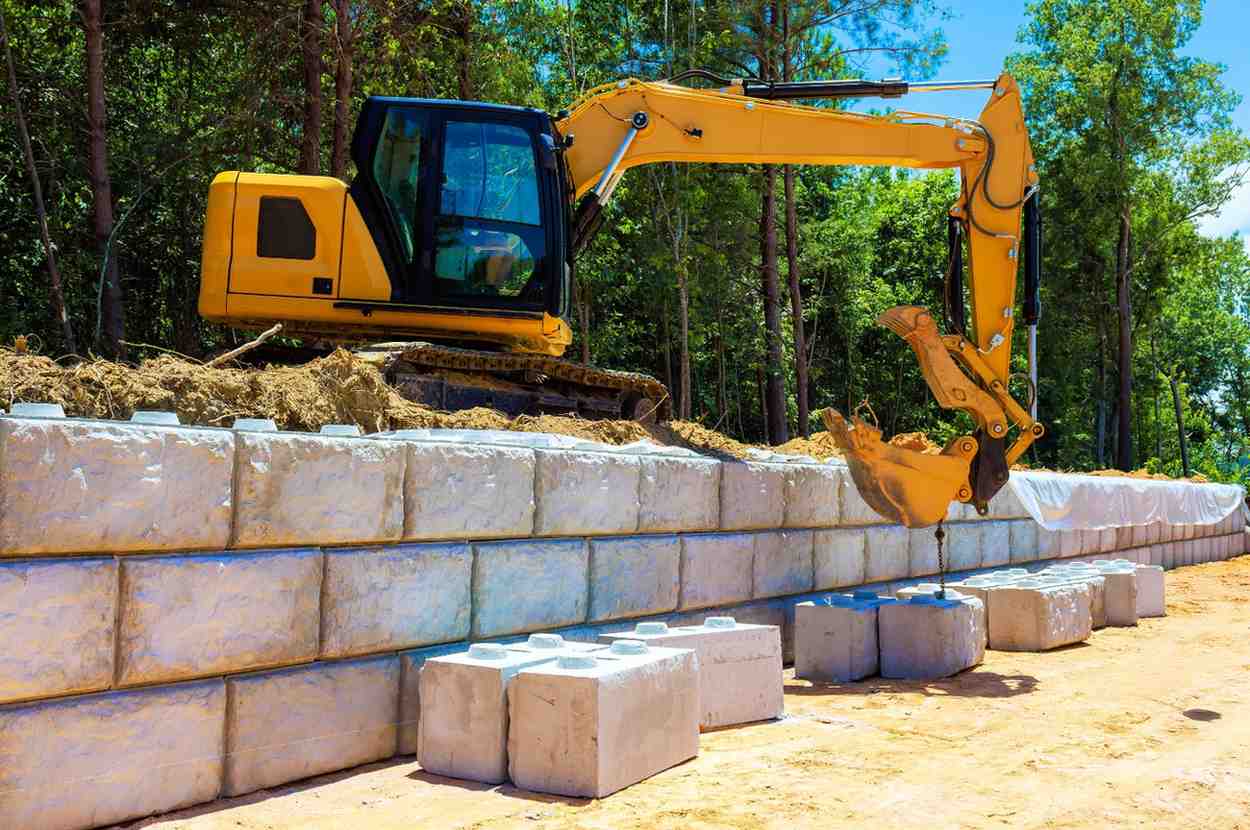 Excavator installing recycled concrete blocks for a retaining wall as part of sustainable construction on the Gold Coast.