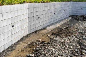 Retaining wall drainage Gold Coast system with concrete wall weep holes and gravel channel for water runoff