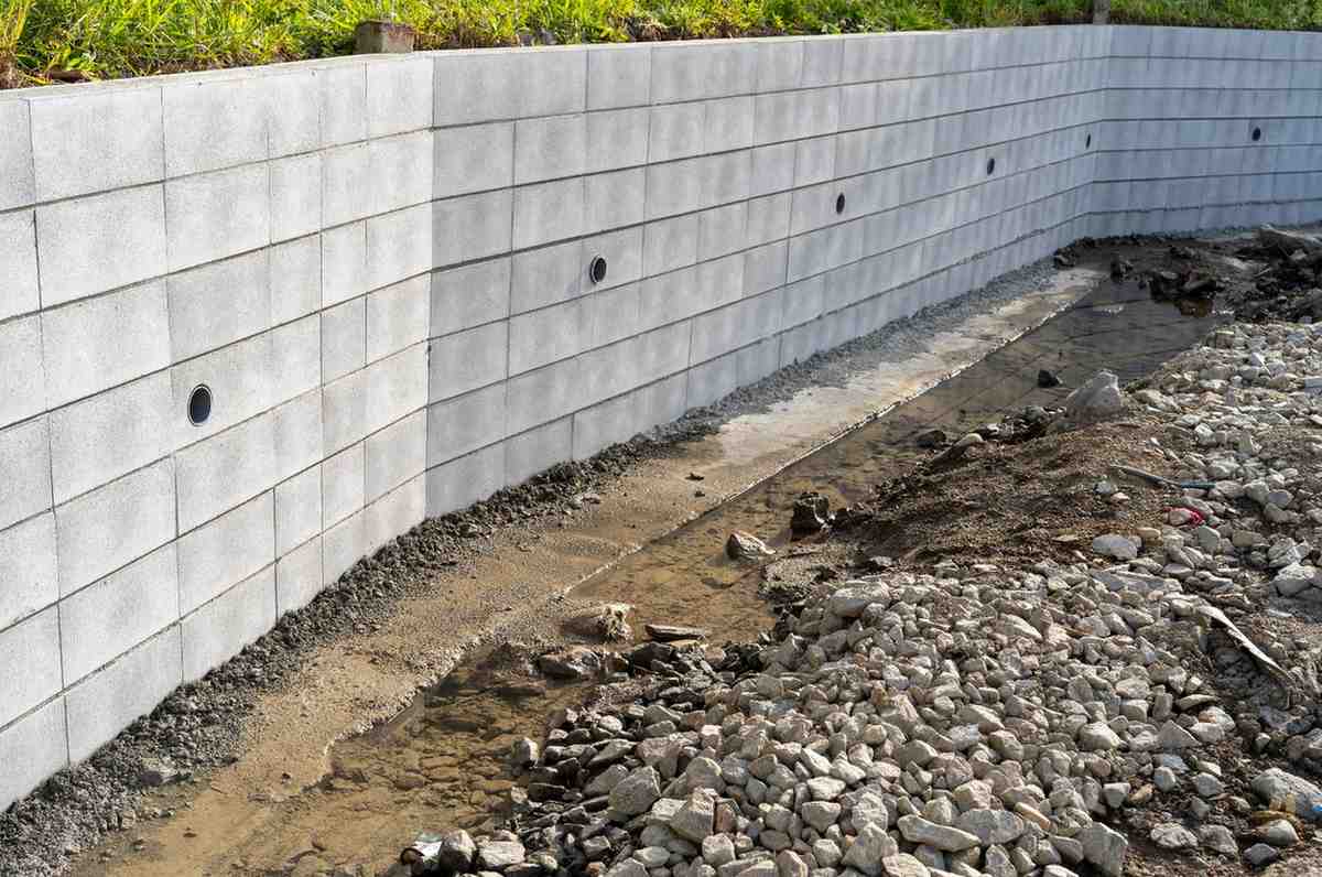 Retaining wall drainage Gold Coast system with concrete wall weep holes and gravel channel for water runoff