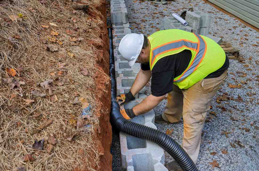 Contractor installing drainage behind blocks to prepare a retaining wall project on the Gold Coast.