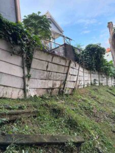 Emergency retaining wall leaning and separating on a slope below a house after heavy rain