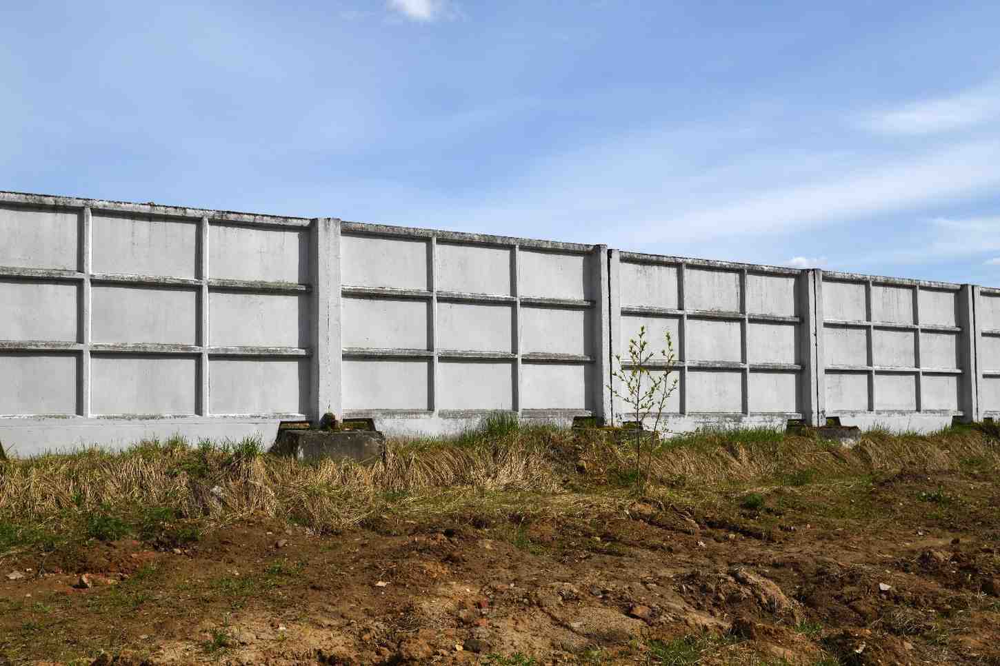 Precast concrete panel retaining wall running along a civil construction site under a clear Gold Coast sky