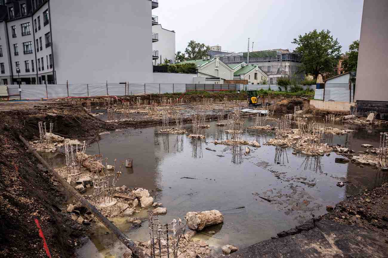 Standing water covering saturated ground around exposed rebar footings on a stalled building site