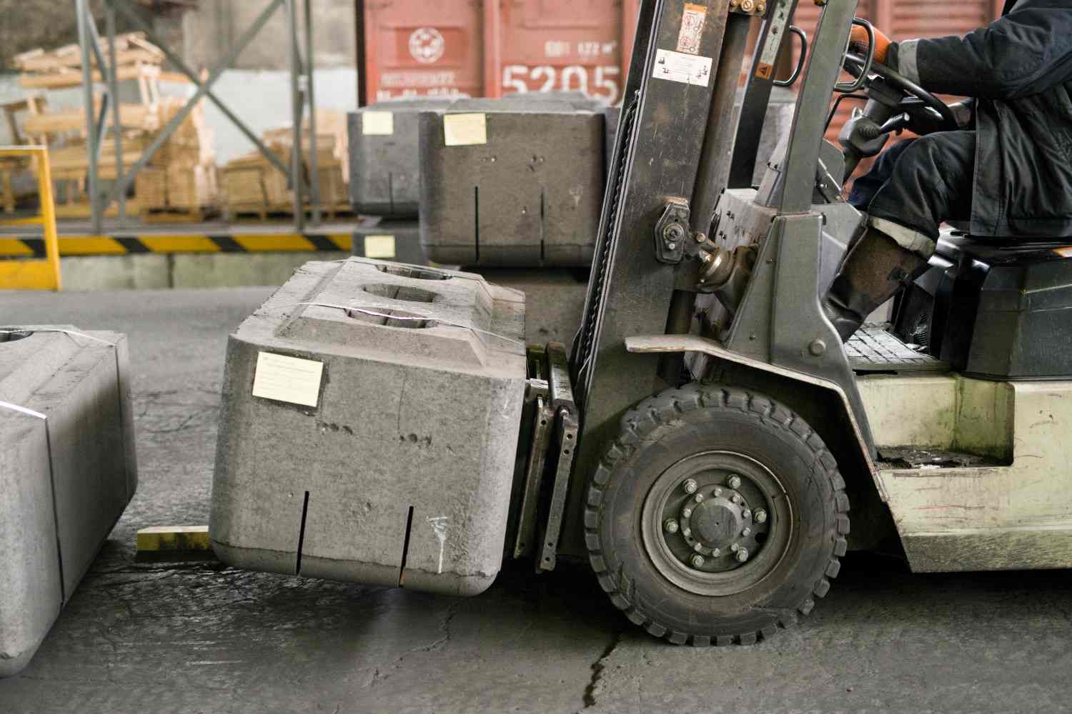 Forklift moving a large precast concrete block in an industrial storage yard