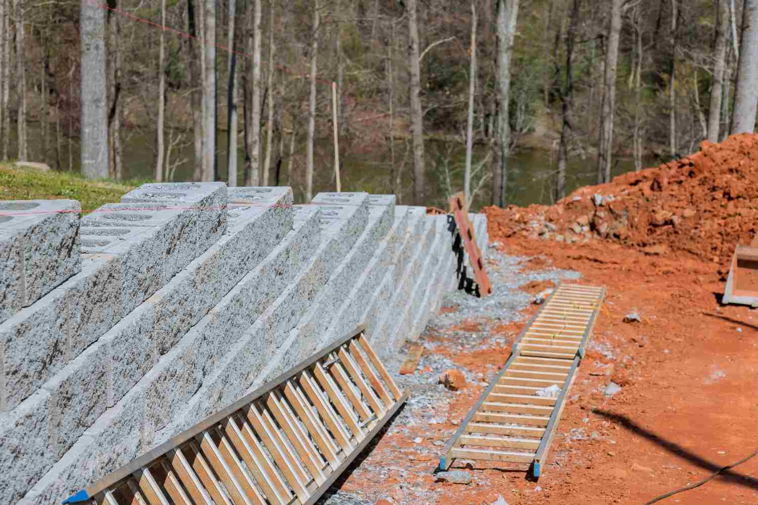 Temporary retaining wall of stacked precast blocks around a staged excavation